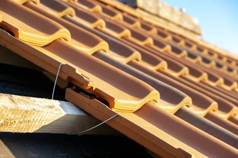 Closeup of metal montage anchor for installation of yellow ceramic roofing tiles