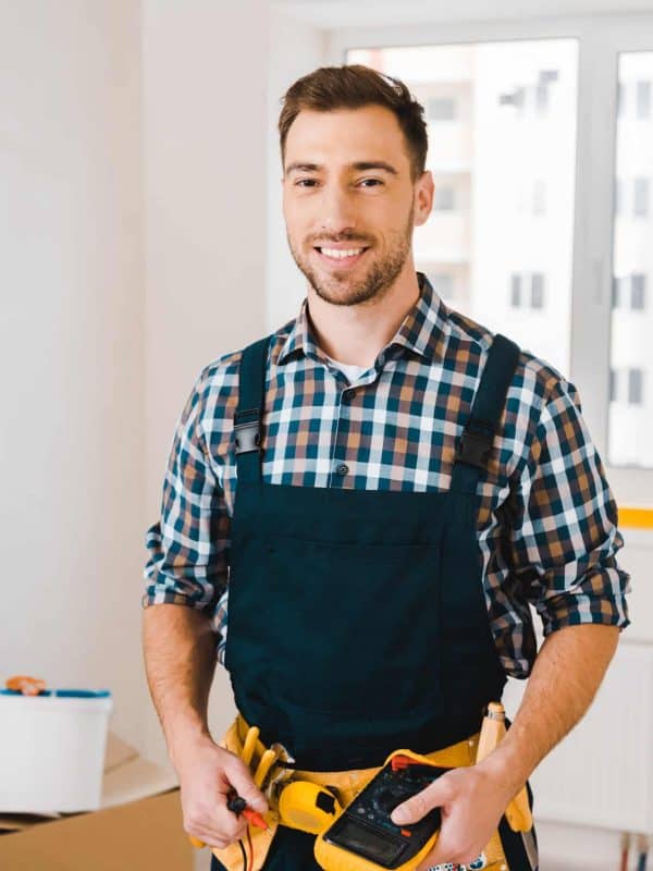 handsome handyman smiling while holding digital multimeter