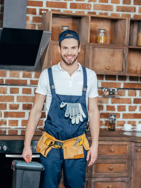 professional home master with toolbox and tool belt smiling at camera