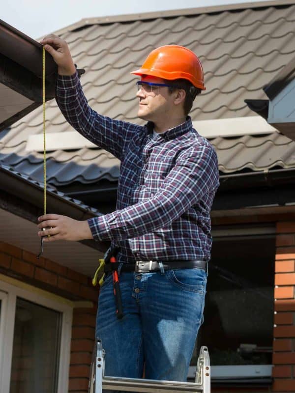 professional worker measuring height of roof with tape