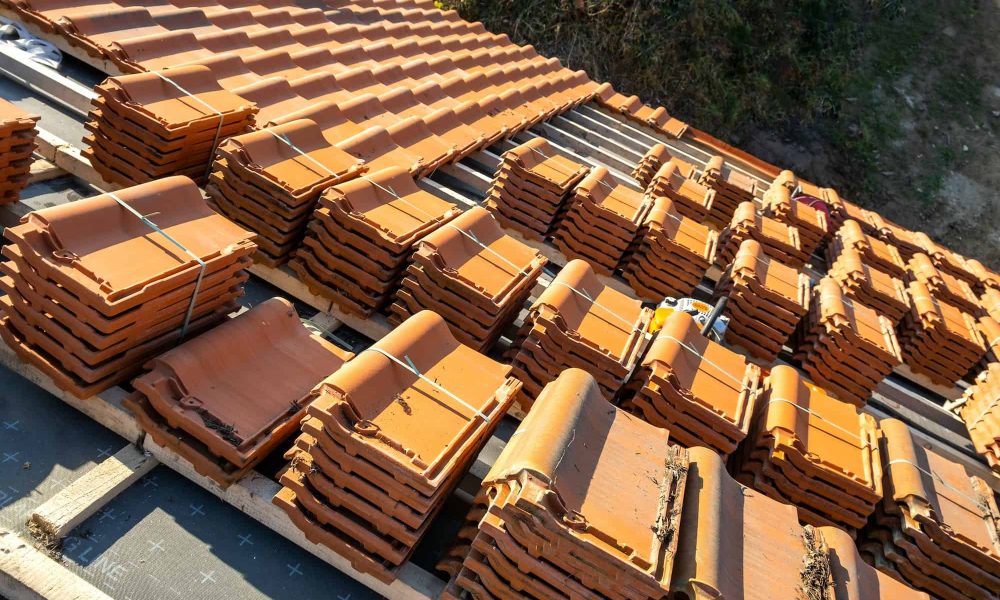 Stacks of yellow ceramic roofing tiles for covering residential building roof under construction