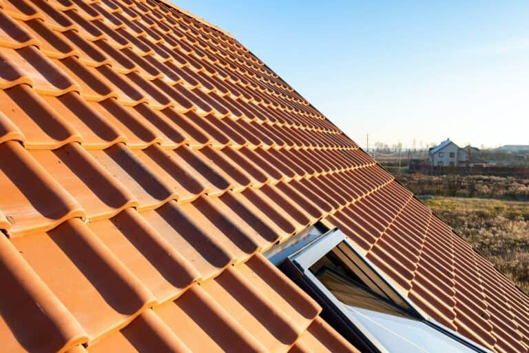 Overlapping rows of yellow ceramic roofing tiles covering residential building roof