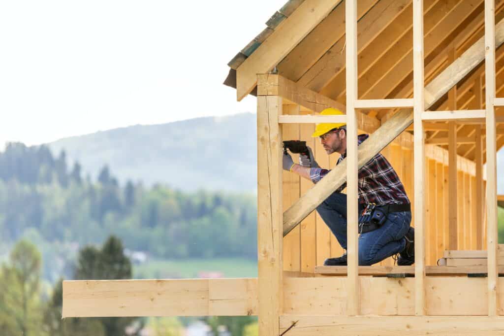 Roofer builder working on roof structure at construction site