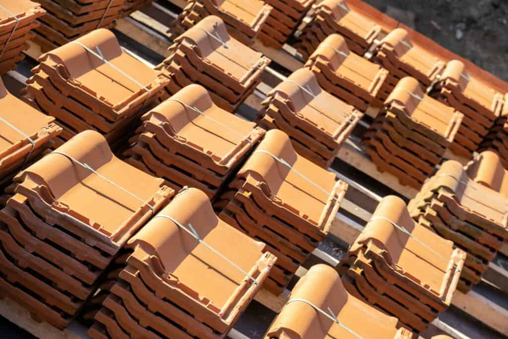 Stacks of yellow ceramic roofing tiles for covering residential building roof under construction.